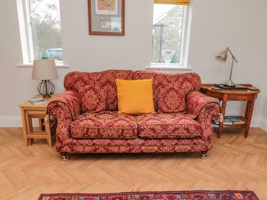 A patterned sofa with pillows between two wooden side tables with lamps in a room at High Barns Cottage Longhorsley near Morpeth
