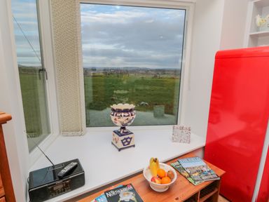 A kitchen window with a radio remote and fruit bowl on a wooden surface beside a red refrigerator at High Barns Cottage Longhorsley near Morpeth