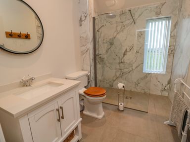 A bathroom with a white vanity and sink a toilet with a wooden seat and a walk in shower at High Barns Cottage in Longhorsley near Morpeth