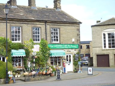 The exterior of The Dalesman Cafe Tea Rooms with green awnings and baskets outside in Gargrave