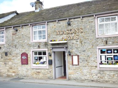 Stone building with windows and flowers on sills and a sign reading Masons Arms