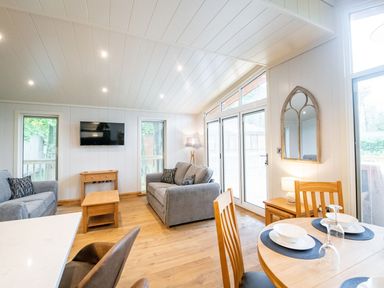 A living room with two grey sofas a wooden coffee table a wall-mounted TV and dining table at Bluebell Lodge in Gargrave