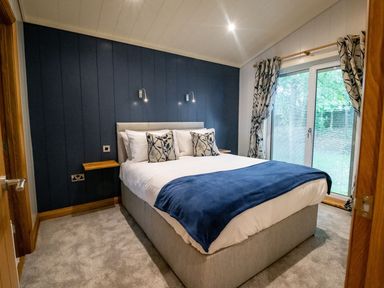 A bedroom with a double bed and blue wall at Bluebell Lodge in Gargrave