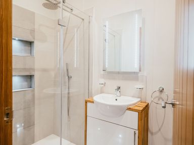 A bathroom with a walk-in shower and a sink with a mirror at Bluebell Lodge in Gargrave