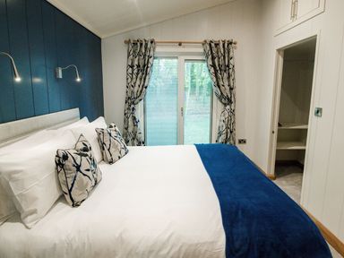 A bedroom with a bed white bedding blue throw pillows and a blue wall at Bluebell Lodge in Gargrave