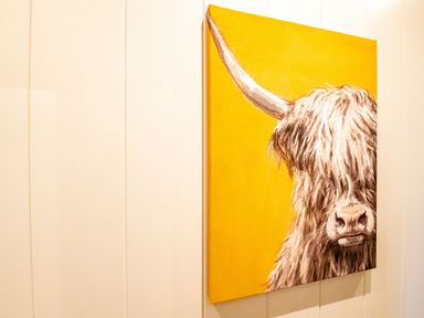 A painting of a highland cow with long horns on a yellow background at Bluebell Lodge in Gargrave