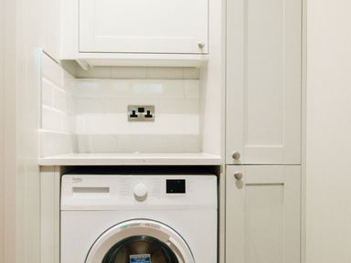 A laundry area with a front loading washing machine built into cabinetry at Bluebell Lodge in Gargrave