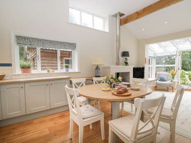 A dining area with a round wooden table and white chairs in a kitchen space at The Roost in Cheriton near Alresford