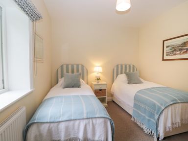 A bedroom with two single beds side by side a nightstand with a lamp between at The Roost in Cheriton near Alresford