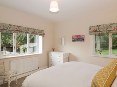 A bedroom with a bed white dresser two windows and floral valances at The Roost in Cheriton near Alresford