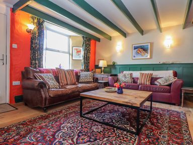 A living room with two leather sofas a wooden coffee table and a patterned rug at Trewenna Roseland Tregony
