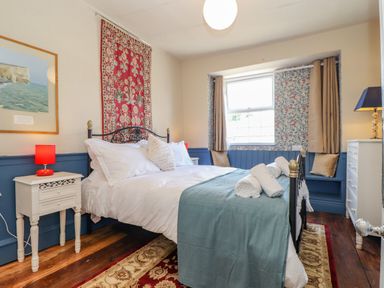 A bedroom with a double bed white bedding blue throw and bedside tables with lamps at Trewenna in Roseland Tregony