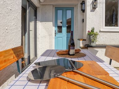 An outdoor table with bread a wine bottle and pizza peels near a blue door at Trewenna in Roseland Tregony