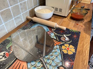A kitchen counter with a rolling pin a bowl of dough a pizza peel a bowl of tomato sauce and a microwave at Trewenna Roseland Tregony