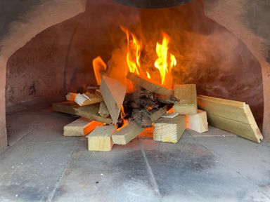 Fire burning inside a brick or stone oven with wooden planks at Trewenna Roseland Tregony