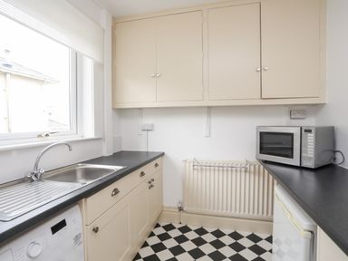 A kitchen with a sink washing machine microwave and cabinets at Awelfryn in Criccieth