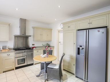A kitchen with a round table and two chairs a stainless steel oven and refrigerator at Awelfryn in Criccieth