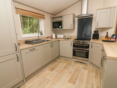 A kitchen with cabinets a sink oven microwave and utensils at Barneys Retreat in Carnforth