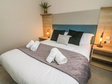 A bedroom with a bed with pillows and rolled towels on a quilt at Barneys Retreat in Carnforth