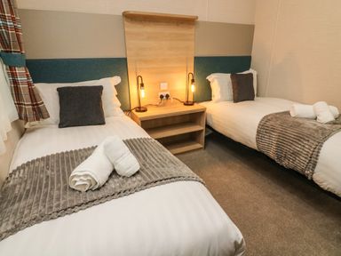 A bedroom with two single beds bedside table two lamps and rolled towels at Barneys Retreat in Carnforth