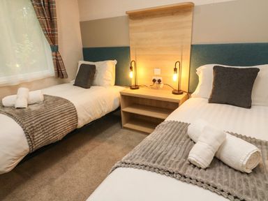 A bedroom with two single beds side by side with bedside table and lamps at Barneys Retreat in Carnforth