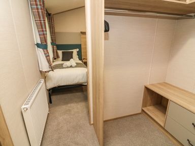A bedroom with a single bed and a radiator next to a closet with shelves and drawers at Barneys Retreat in Carnforth