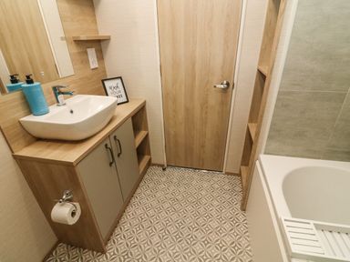 A bathroom with a sink on a wooden cabinet a bathtub and a wooden door at Barneys Retreat in Carnforth