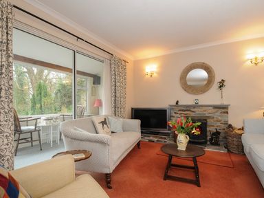 A living room with sofas a coffee table with flowers a fireplace and a television at Kirland in St Kew Highway