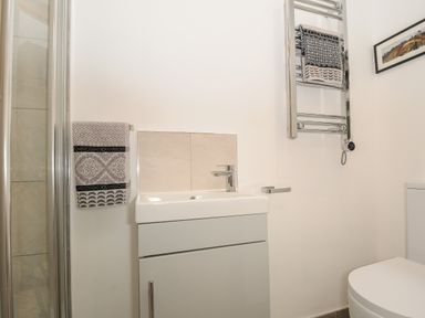 A bathroom with a sink and cabinet a towel rack with towels a shower and a toilet at Kirland in St Kew Highway