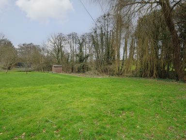 An open grassy field with trees and a wooden shed at Kirland in St Kew Highway