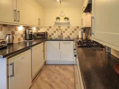 A kitchen with a gas stove microwave coffee maker and kettle at Jennys in Hawkshead