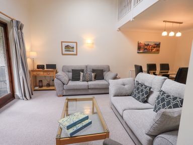 A living room with two grey sofas and a glass coffee table with books at Beechside in Ambleside