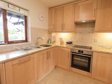 A kitchen with wooden cabinets a window a sink an oven and countertop at Beechside in Ambleside