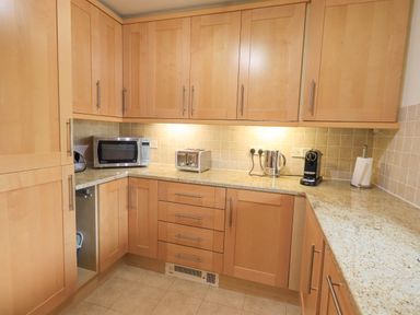 A kitchen with wooden cabinets a microwave a toaster a kettle a coffee machine and a paper towel holder at Beechside in Ambleside