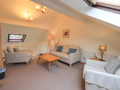 A sitting room with three sofas a wooden coffee table lamps and skylight windows at Beechside in Ambleside