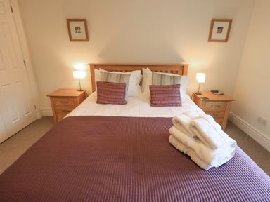 A bedroom with a double bed two bedside tables with lamps folded towels on the bed at Beechside in Ambleside