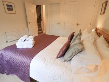 A bedroom with a bed made with white linens and purple throw at Beechside in Ambleside