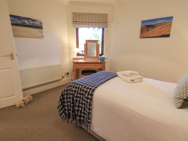 A bedroom with a single bed a desk with a mirror and lamp and two landscape pictures on the wall at Beechside in Ambleside