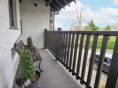 A balcony with a bench and potted plants overlooking a street with a parked car at Beechside in Ambleside