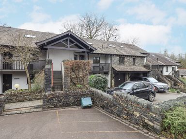 An apartment building with stone walls cars parked outside and stairs leading to the entrance at Beechside in Ambleside