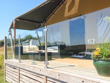 An outdoor deck with seating area and glass railing at Semira Tent Lodge in Blackawton