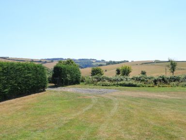 A grassy field with hedges and a gate overlooking rolling hills at Semira Tent Lodge in Blackawton
