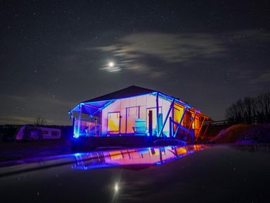 A tent lodge illuminated with colored lights under a starry night sky at Semira Tent Lodge in Blackawton