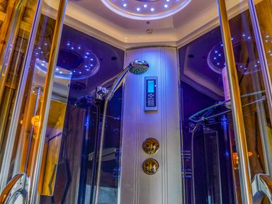 An enclosed shower cabin with a handheld showerhead control knobs digital panel and blue LED lights at Semira Tent Lodge in Blackawton