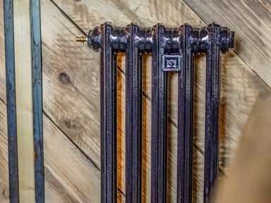 A close-up of a black cast iron radiator against a wooden wall at Semira Tent Lodge in Blackawton