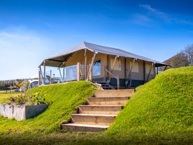 A tent lodge with wooden stairs and a grassy mound at Semira Tent Lodge in Blackawton