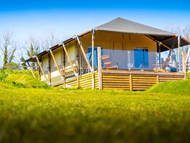 A tent lodge with wooden deck and chairs on grass at Semira Tent Lodge in Blackawton