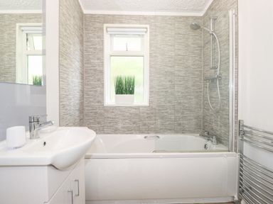A bathroom with a bathtub shower sink window and a plant at Honeysuckle Lodge Thirlmere 14 White Cross Bay near Windermere