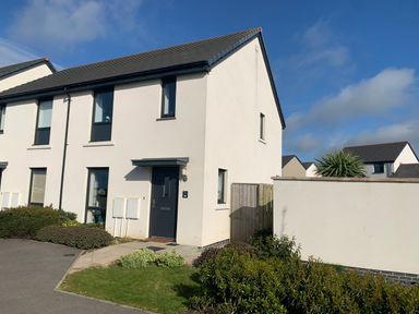 The exterior of a two-story end terrace house with a dark front door and several windows in a residential area at 2 Boathouse Terrace in Mawgan Porth
