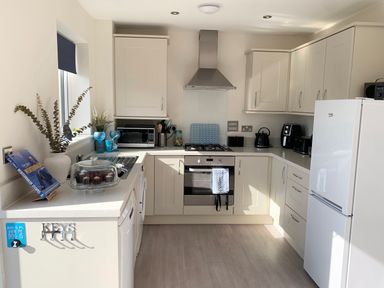 A kitchen with white cabinets a refrigerator an oven a microwave and kitchen utensils at 2 Boathouse Terrace in Mawgan Porth
